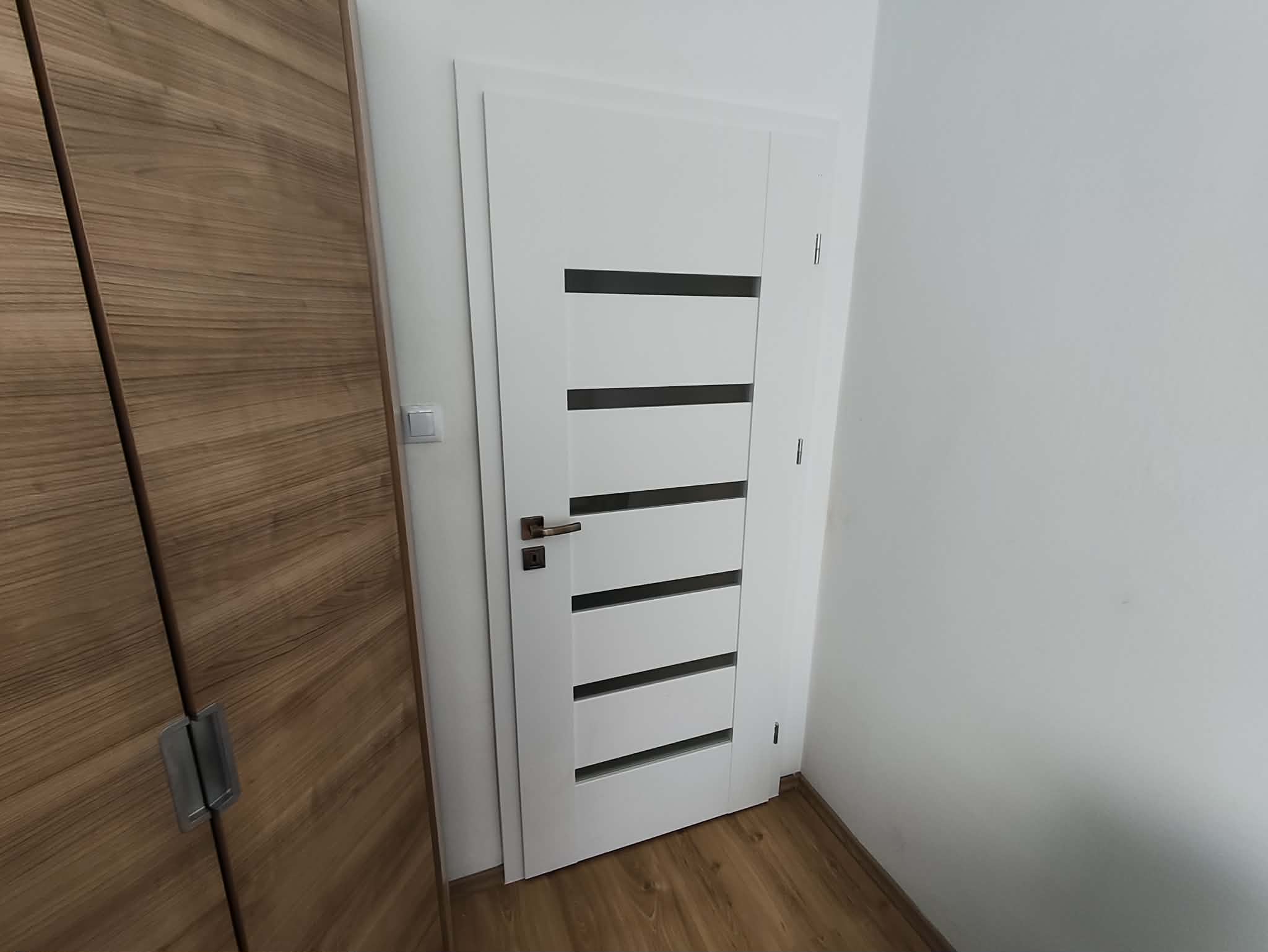 Jasne skrzydło z poziomymi przeszkleniami w korytarzu.